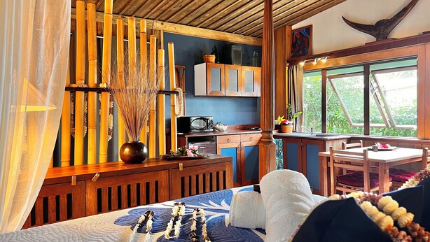 Un dormitorio acogedor con cama, cabecera de madera, mesita de noche y ventana con vista a la vegetación.