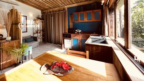 Una cocina moderna con gabinetes de madera, un lavamanos integrado y una zona de comedor con una mesa de madera.
