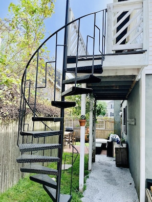 A spiral staircase leading to an upper level, surrounded by a wooden fence and a gravel path.