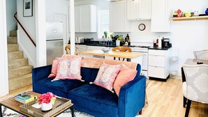 A modern living room with a blue sofa, a coffee table with books and flowers, and a staircase leading to another room. - Private unique home short 5 minutes walk to the beach and the bay. (Hull)