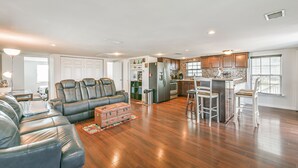 A spacious living room with a leather sectional sofa, a kitchen with wooden cabinets, and a dining area with bar stools. - Awesome Bay View Home with Two Living Areas!  Pets welcome! (Galveston)