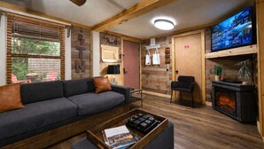 Ein gemütliches Wohnzimmer mit einer Couch, einem Kamin, einem Fernseher und einer Holzwand.