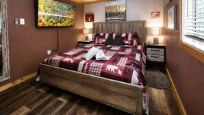 Ein Schlafzimmer mit einem hölzernen Bett, einem großen Gemälde, einem Nachttisch und einem Fenster mit Jalousien.