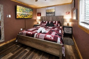 Una camera da letto con un letto di legno, un quadro di grandi dimensioni, un comodino e una finestra con persiane.