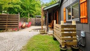 Eine Terrassenfläche mit Feuerstelle, Sitzgelegenheiten im Freien und einem Holzzaun.