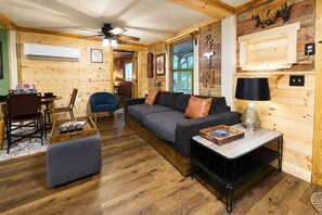 A cozy room with a sofa, a coffee table, a chair, and a dining table.