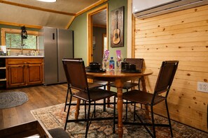 A cozy kitchen with wooden cabinets, a refrigerator, and a dining table with chairs.