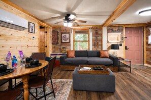 Un intérieur de chalet chaleureux avec un coin repas, un canapé et un ventilateur de plafond.