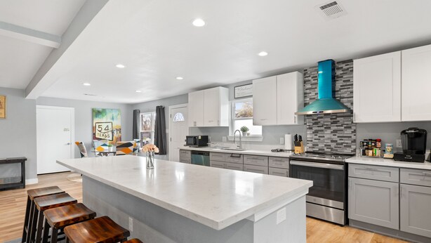 Una cocina moderna con una isla grande, electrodomésticos de acero inoxidable y un salpicadero gris.