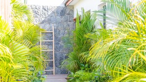 A wooden pathway leading to a stone wall, surrounded by lush green foliage. - Villa Cute | Ocean View - Located in  Wonderful Toiny with Private Pool (Toiny)