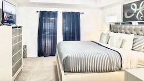 A bedroom with a bed, a dresser, a television, and a ceiling light. - Entire home with pool for long and short stay. Fun for everyone.  (Port St. Lucie)