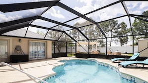 An outdoor swimming pool with a covered area, lounge chairs, and a view of the surrounding landscape. - Entire home with pool for long and short stay. Fun for everyone.  (Port St. Lucie)