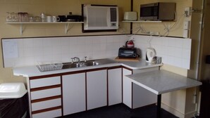 A compact kitchen with a sink, a microwave, and a toaster. There are cabinets and a countertop.