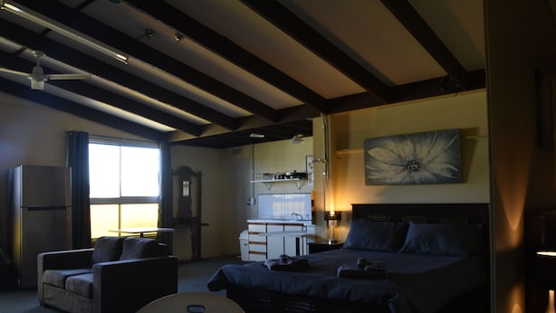 A bedroom with a bed, a desk, a chair, and a television.