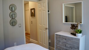 Un dormitorio con cama, cómoda, espejo y aire acondicionado de pared.