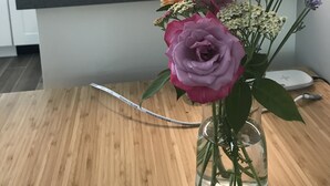 Una cocina con encimera de madera, un florero con flores y una estufa al fondo.