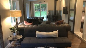 A cozy living room with a dark leather sofa, a small round table with a lamp, and a white furry rug.