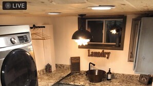 A compact laundry room with a washing machine, a sink, and a small rug.