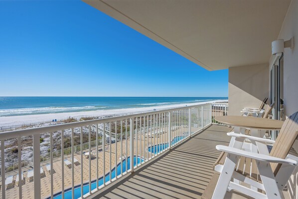 A balcony with a view of the beach and ocean.