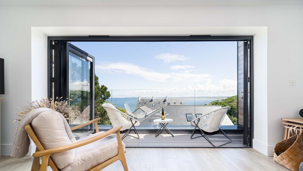 Un salon moderne doté d’une grande porte vitrée donnant sur un balcon avec vue sur la mer.