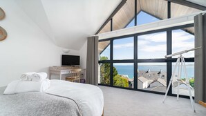 Une chambre avec une grande fenêtre, un lit, un bureau et un télescope.
