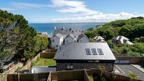 Un quartier résidentiel situé sur la côte, avec des maisons, un ciel dégagé et une vue sur la mer.