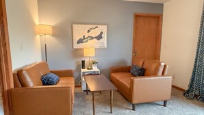A living room with two brown leather sofas, a small wooden coffee table, and a map on the wall. - Escape to the Lake! Walk to water & local dining! (Lake Geneva)