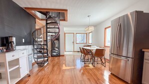 A modern kitchen with a spiral staircase, stainless steel appliances, and a dining area with a table and chairs. - Escape to the Lake! Walk to water & local dining! (Lake Geneva)