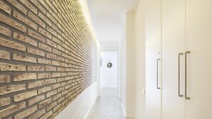 Ein Flur mit Backsteinwand, weißen Türen und einem hellen Boden.