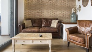 Ein Wohnzimmer mit Backsteinwand, Ledermöbeln und einem Holztisch.