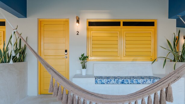 A hammock in a room with two yellow doors, a white wall, and a blue patterned cushion. - Mare Lindo studio near Malecon Progreso (Progreso)