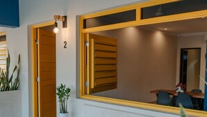 A modern reception area with a wooden door marked '2', a bench with a blue and white pattern, and a large mirror reflecting the interior. - Mare Lindo studio near Malecon Progreso (Progreso)