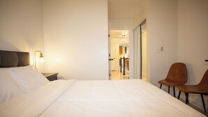 A hotel room with a large bed, a nightstand, a lamp, and two chairs.