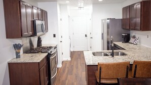 A kitchen with wooden cabinets, stainless steel appliances, granite countertops, and a central island with seating.