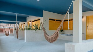A spacious outdoor area with concrete flooring, multiple hammocks, and a building with yellow doors and windows. - Mare Lindo open studio near Malecon Progreso (Progreso)