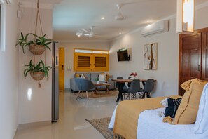 Un salon moderne avec un lit, un coin repas et une cuisine en arrière-plan.