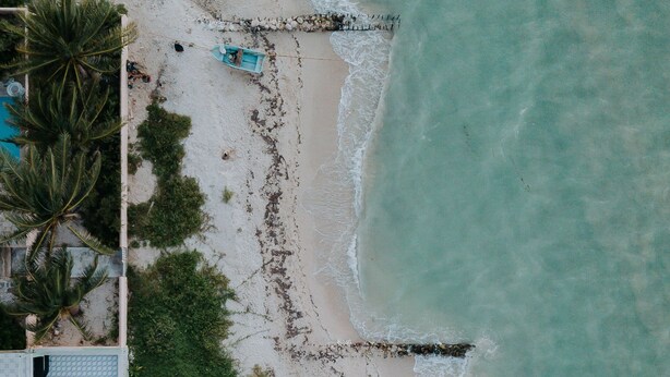 An aerial view of a beach with boats, a pier, and a building with a pool. - Mare Lindo open studio near Malecon Progreso (Progreso)