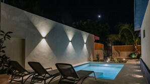 A swimming pool area with lounge chairs and wall-mounted lights. - Mare Lindo open studio near Malecon Progreso (Progreso)