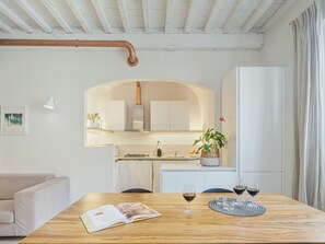 A modern kitchen with white cabinets, a central island, and a dining area with a table set for two.
