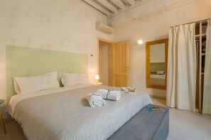 A hotel room with a bed, a bedside table, a lamp, a mirror, and a wardrobe.