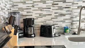 Et køkken med et sort komfur, en kaffemaskine og en brødrister på bordpladen.