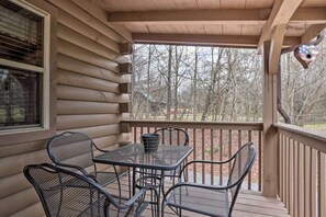 A covered porch with a table and chairs, a window, and a birdhouse. - Cozy `American Dream` Cabin w/ Hot Tub, Loft & BBQ!!! (Cosby)
