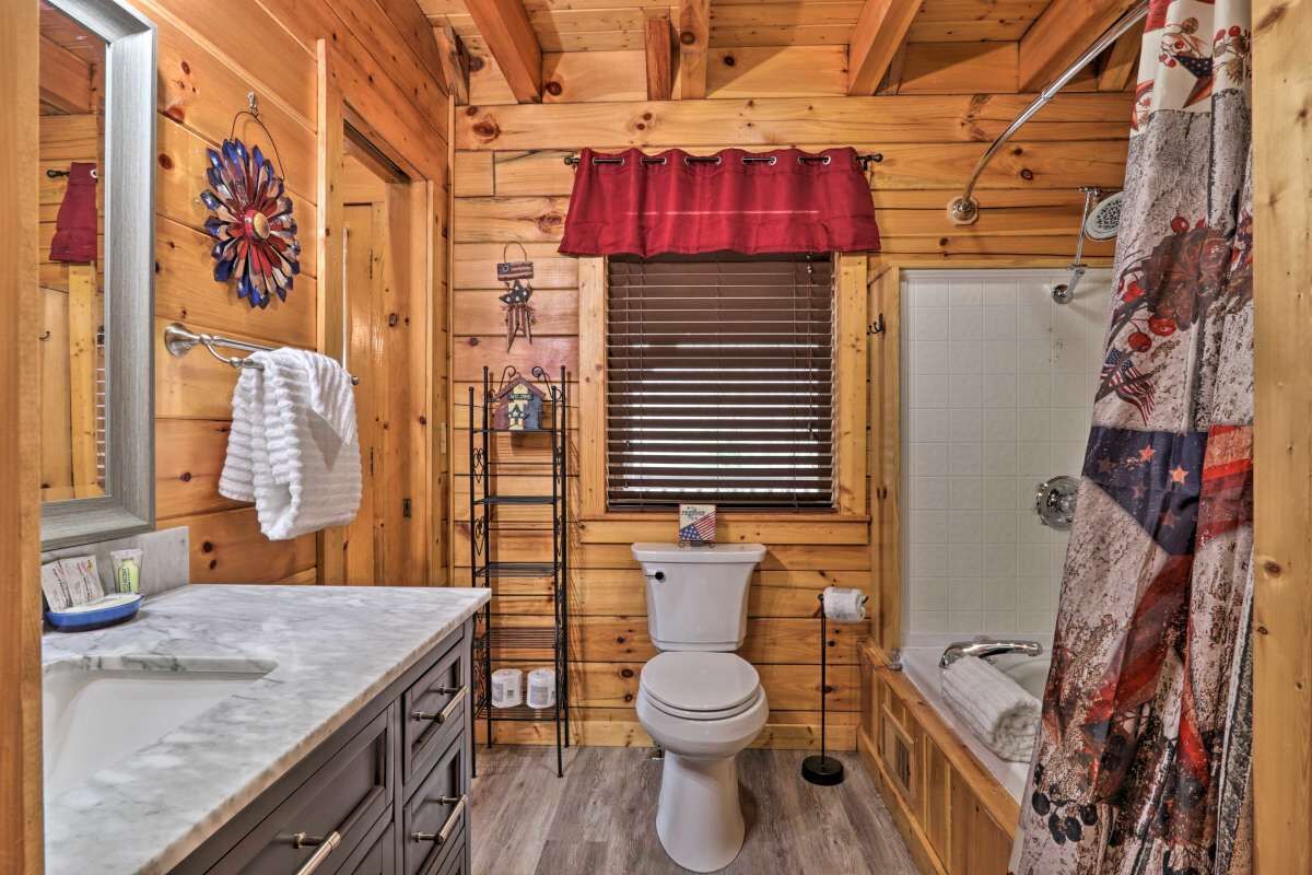 Baño de una cabaña de madera con inodoro, lavabo y ducha.