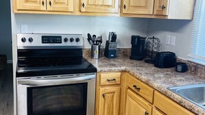 A kitchen with wooden cabinets, a stainless steel stove, and a granite countertop. - Secret Hideaway (Rossville)