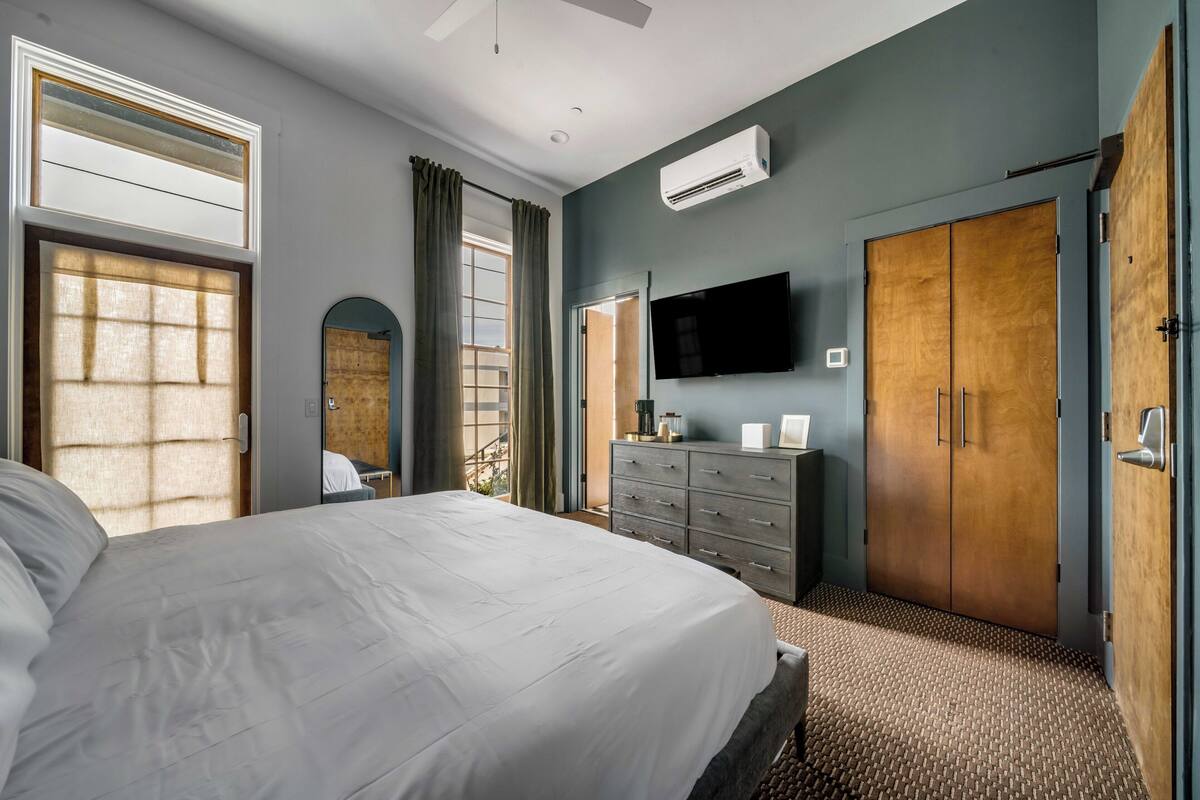 A bedroom with a bed, a dresser, a television, and a wardrobe.