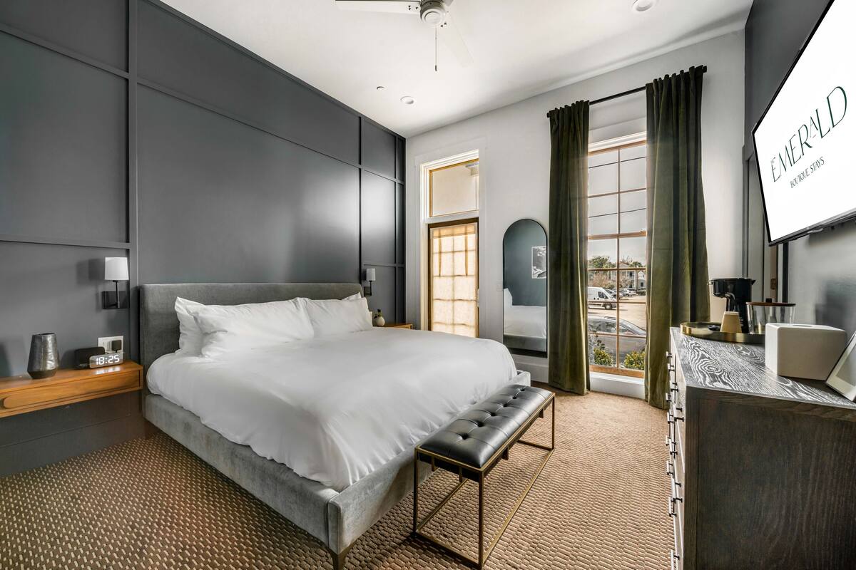 A modern hotel room with a large bed, a desk, and a view of the outside.