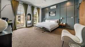 Une chambre à coucher avec un lit, une chaise, un bureau et une vue sur l’extérieur.