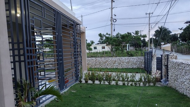 A modern building with a geometric metal gate and a well-maintained lawn. - Spacious and unique house closed to beaches & natural monuments! (Cabrera)