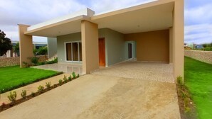 A modern house with a covered patio, a well-maintained lawn, and a clear sky. - Spacious and unique house closed to beaches & natural monuments! (Cabrera)
