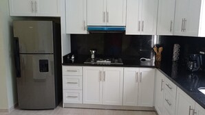 A modern kitchen with white cabinets, a stainless steel refrigerator, a gas stove, and a black countertop. - Spacious and unique house closed to beaches & natural monuments! (Cabrera)